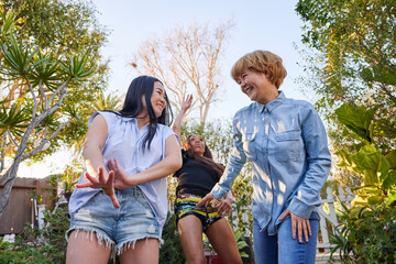 three women dancing in garden laughing