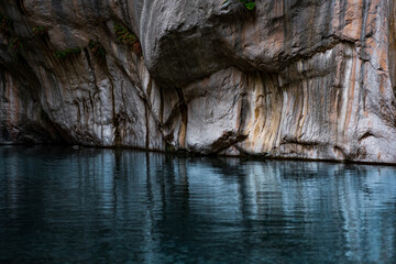 clean blue river with rocky banks at the bottom of a deep canyon