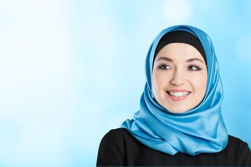 A young smiling muslim woman wearing a hijab over blur background.