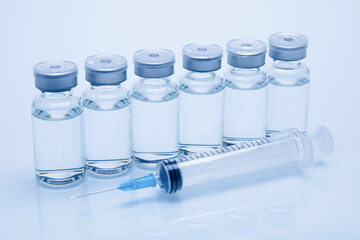 Closeup of medicine or injection vials with liquid and a syringe isolated on a white background
