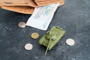 War in Ukraine and sanctions against Russia concept. Wallet with Russian rubles and a toy tank on a...