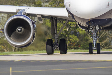 View of a Jet engine at the airport runway with trees in the background