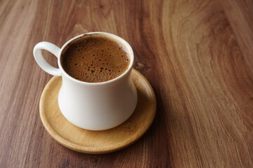 a cup of foamy turkish coffee on the wooden table