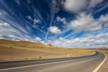 Widok z drogi na dwa wiatraki. Krajobrazy na wyspach kanaryjskich, Lanzarote. Piękne chmury na niebieskim niebie. © anettastar