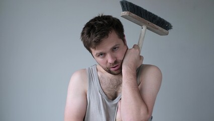 Tired young man with mop on white background