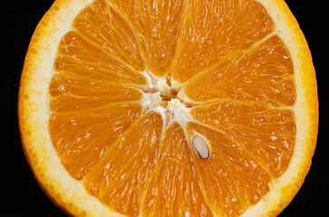 A half slice section of a single orange on a black background revealing the inside segments and structure.