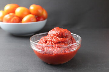 tomato sauce pasta in a glass bowl next to tomatoes on a black background with a place for text