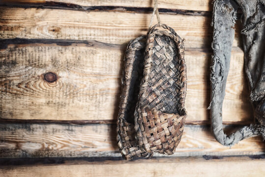 Old bast shoes on a wooden wall.