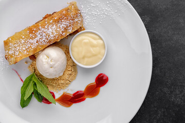 Dessert strudel with apples and ice cream, , on a dark background