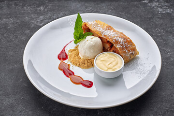 Dessert strudel with apples and ice cream, , on a dark background