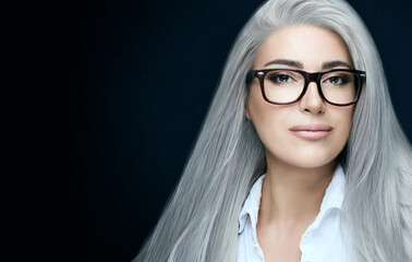 Fototapeta premium Women eyewear. Stylish silver hair woman in clear glasses looking at camera. Eyewear banner iover dark blue with copy space