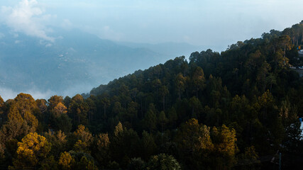 Clouds over the mountains with green trees