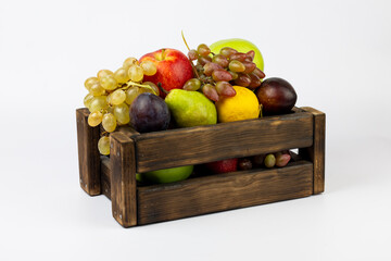 Various fruits in wooden box on white background. Seasonal eco fruit background.