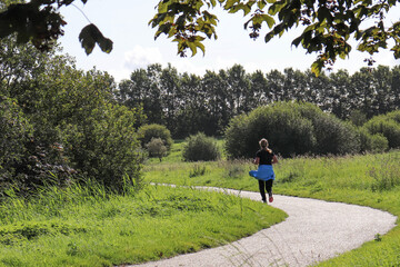 Woman in sportswear is walking along the path in the park on a summer dag. High quality photo