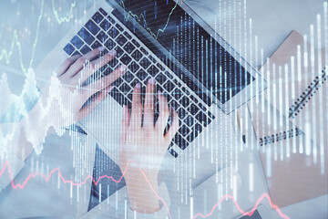 Double exposure of woman hands working on computer and forex graph hologram drawing. Top View. Financial analysis concept.