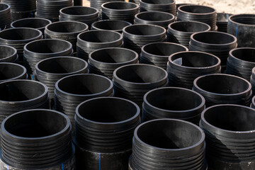 New plastic black pipes for drinking water are stored outside. Repair of water supply in the city...