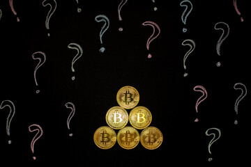 Fototapeta premium Hand holding Bitcoin virtual money against blackboard with question marks.