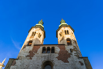 Fototapeta premium Two gothic towers in old Krakow at sunset in the rays of the evening sun against the blue sky
