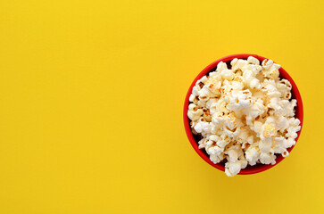 a bucket of popcorn on a yellow background flat lay, copy space - obrazy, fototapety, plakaty
