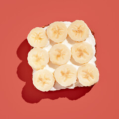 Bread with cream cheese with banana isolated on on red background