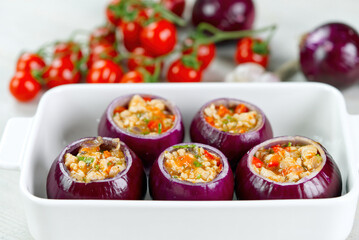 Stuffed onions recipe. Red onions stuffed with meat and vegetables in white bowl ready to bake in the oven. close up