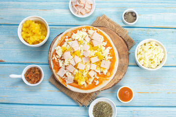 Artisan pizza before baking, with cheese, ham, pineapple, pomodoro sauce, accompanied by flavors