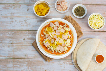 Artisan pizza before baking, with cheese, ham, pineapple, pomodoro sauce, accompanied by flavors