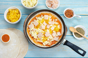 Artisan pizza before baking, with cheese, ham, pineapple, pomodoro sauce, accompanied by flavors