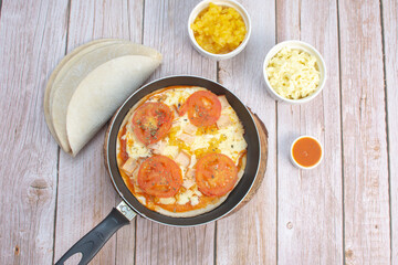 Artisan pizza before baking, with cheese, ham, pineapple, pomodoro sauce, accompanied by flavors