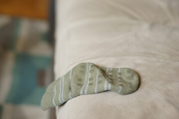 Green single sock for a kid left on the edge of the bed