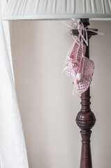 Wicker pink shoes as a decoration hanging on a floor lamp in the bedroom and a piece of white curtains.