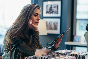 Woman holding vinyl while choosing record in a music shop.