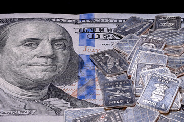 Closeup shot of 1.999 Gram silver bars laying on a $100 US banknote on isolated black background