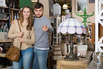 Obraz na płótnie Canvas Loving couple looking for stylish knickknacks in shop of secondhand furniture