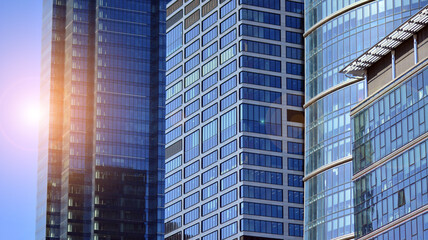 Obraz premium Glass building with transparent facade of the building and blue sky. Structural glass wall reflecting blue sky. Abstract modern architecture fragment. Contemporary architectural background.