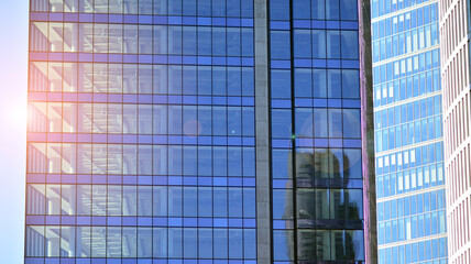 Fototapeta na wymiar Glass building with transparent facade of the building and blue sky. Structural glass wall reflecting blue sky. Abstract modern architecture fragment. Contemporary architectural background.