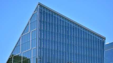 Glass building with transparent facade of the building and blue sky. Structural glass wall reflecting blue sky. Abstract modern architecture fragment. Contemporary architectural background.