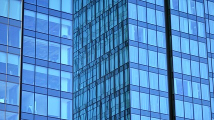 Glass building with transparent facade of the building and blue sky. Structural glass wall reflecting blue sky. Abstract modern architecture fragment. Contemporary architectural background.