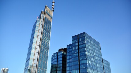 Naklejka premium Glass building with transparent facade of the building and blue sky. Structural glass wall reflecting blue sky. Abstract modern architecture fragment. Contemporary architectural background.
