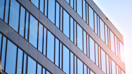 Glass building with transparent facade of the building and blue sky. Structural glass wall reflecting blue sky. Abstract modern architecture fragment. Contemporary architectural background.