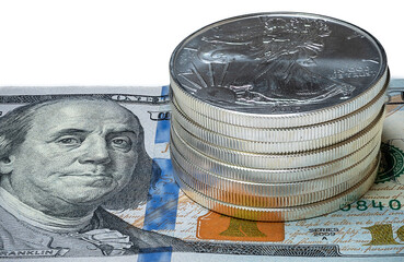 Closeup of Stack of Silver Eagle Coins (Bullions) on a $100 US Bill on isolated white background