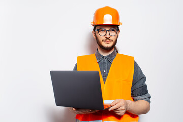 Studio portrait of young confident construction worker on white, using laptop.