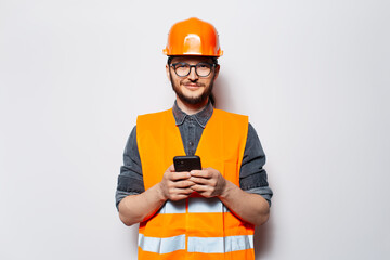Studio portrait of young construction worker on white, using smartphone.