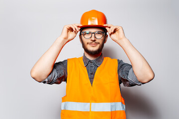 Studio portrait of confident construction worker. Holding hardhat with hands.