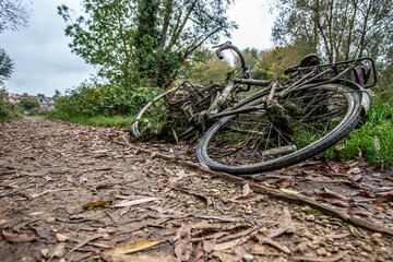 An old, rusty bicycle on the side of a road, footpath