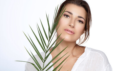 Fototapeta premium Beautiful natural young woman with nude makeup on a flawless skin and a tropical leaf. Natural cosmetics and skincare concept