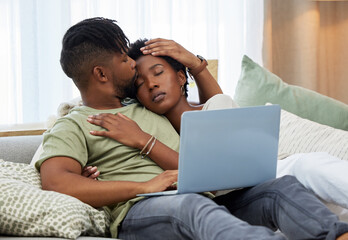 Fototapeta premium Naps are better with him by my side. Shot of a young man kissing his partner on the forehead while using a laptop at home.