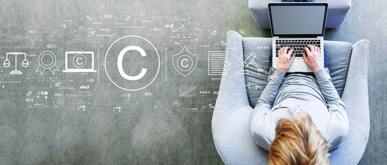 Copyright concept with man using a laptop in a modern gray chair
