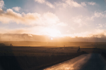 landscape with automated rotating sprinkler system machine with wheels for drop-by-drop irrigation on a sunset © Avelino