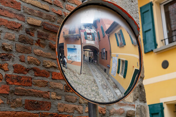 street mirror reflects and distorts the vision of a street in Dozza, in the province of Bologna